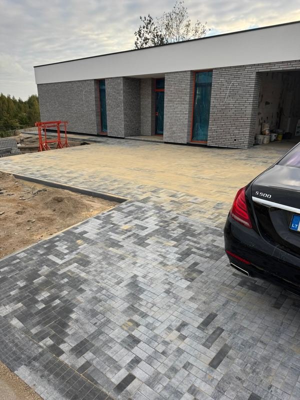 Tamsių trinkelių įvažiavimas prie modernaus gyvenamojo namo