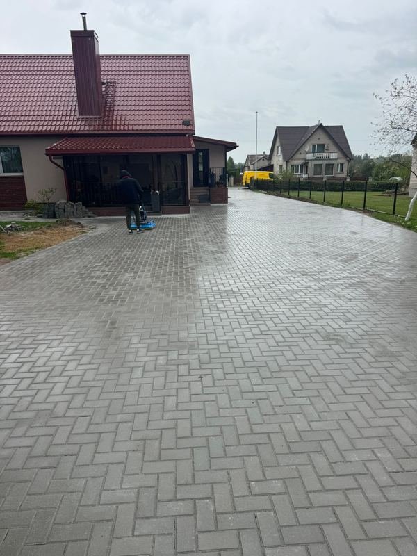 Trinkelių danga kieme prie gyvenamojo namo su raudonu stogu