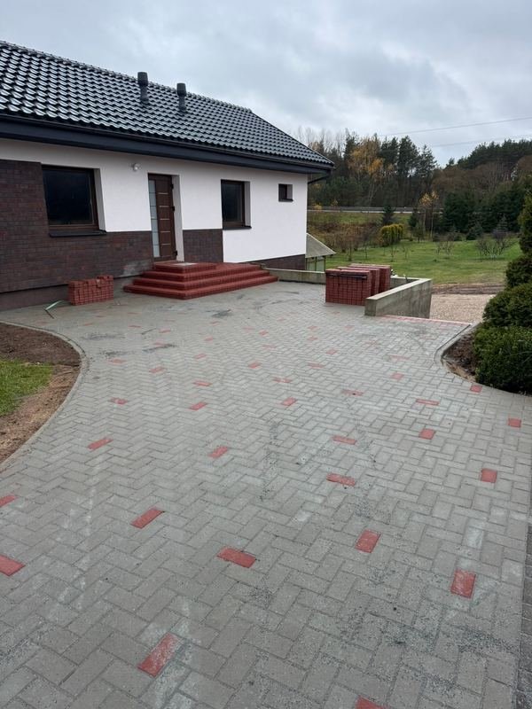 Išklotas kiemas su trinkelių danga ir apželdintomis vejomis