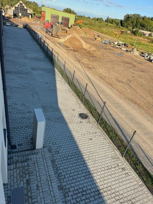 Ilgas trinkelių takas palei pastato sieną su lietaus nuvedimu